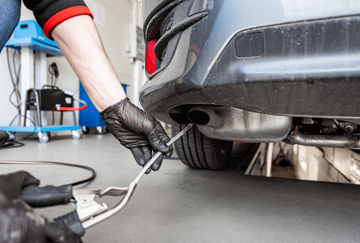 Mechanic performing car exhaust emissions test.