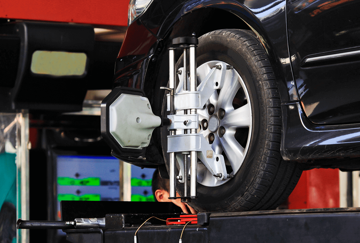 Car undergoing wheel alignment on lift.