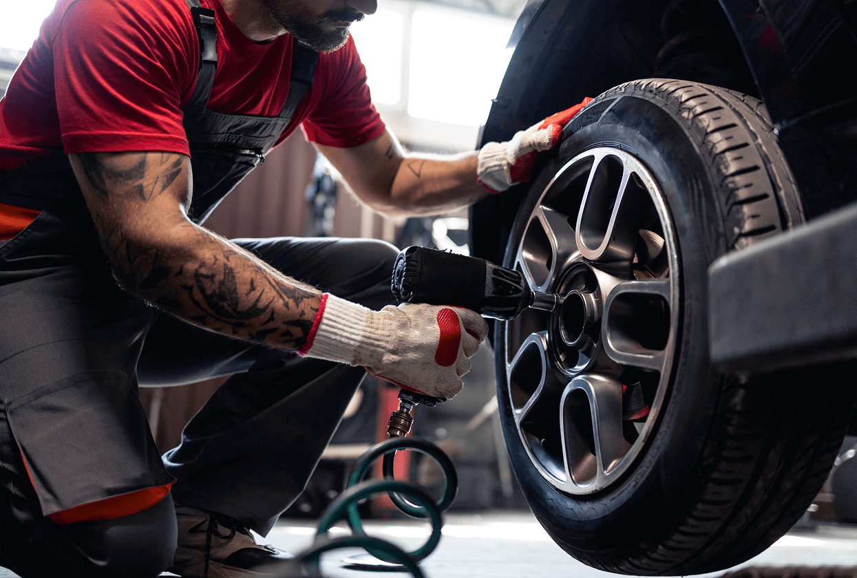 Mechanic tightening car wheel with tool.