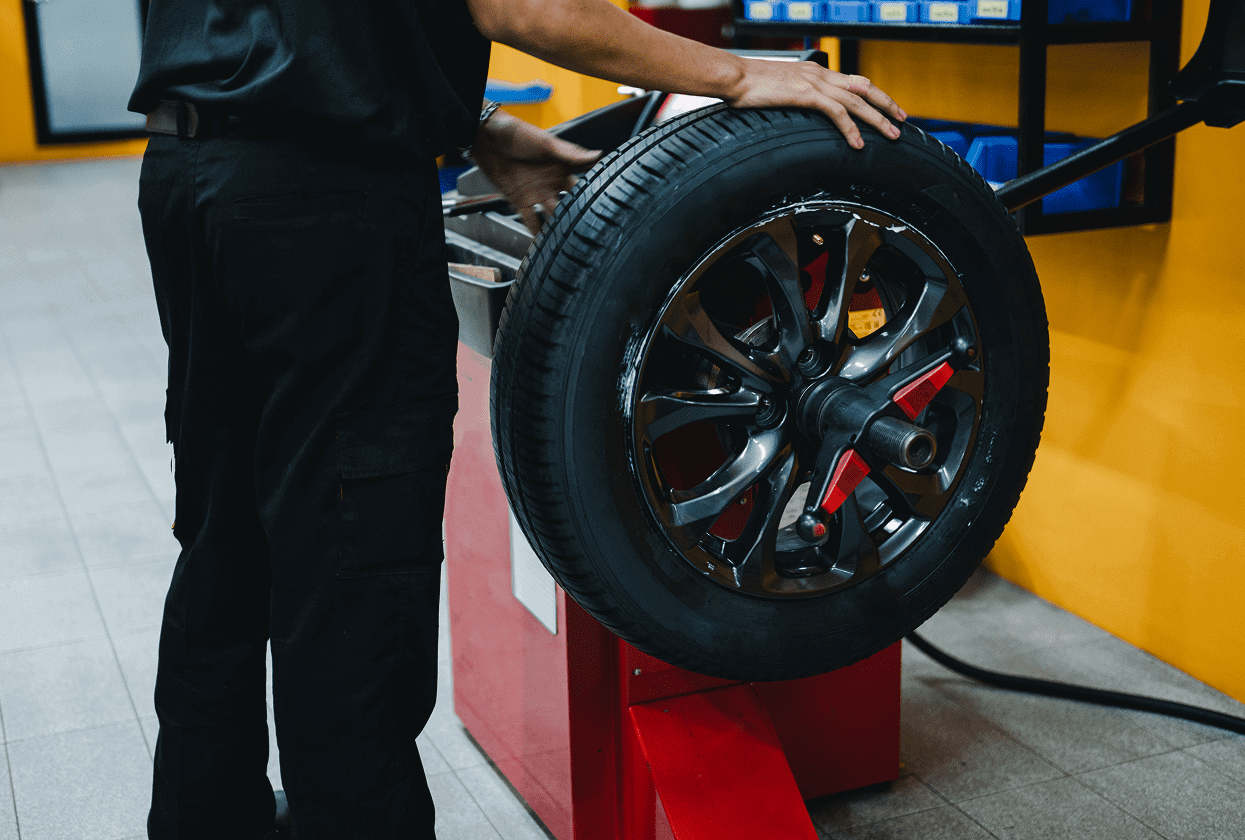 Mechanic balancing a car tire on machine.