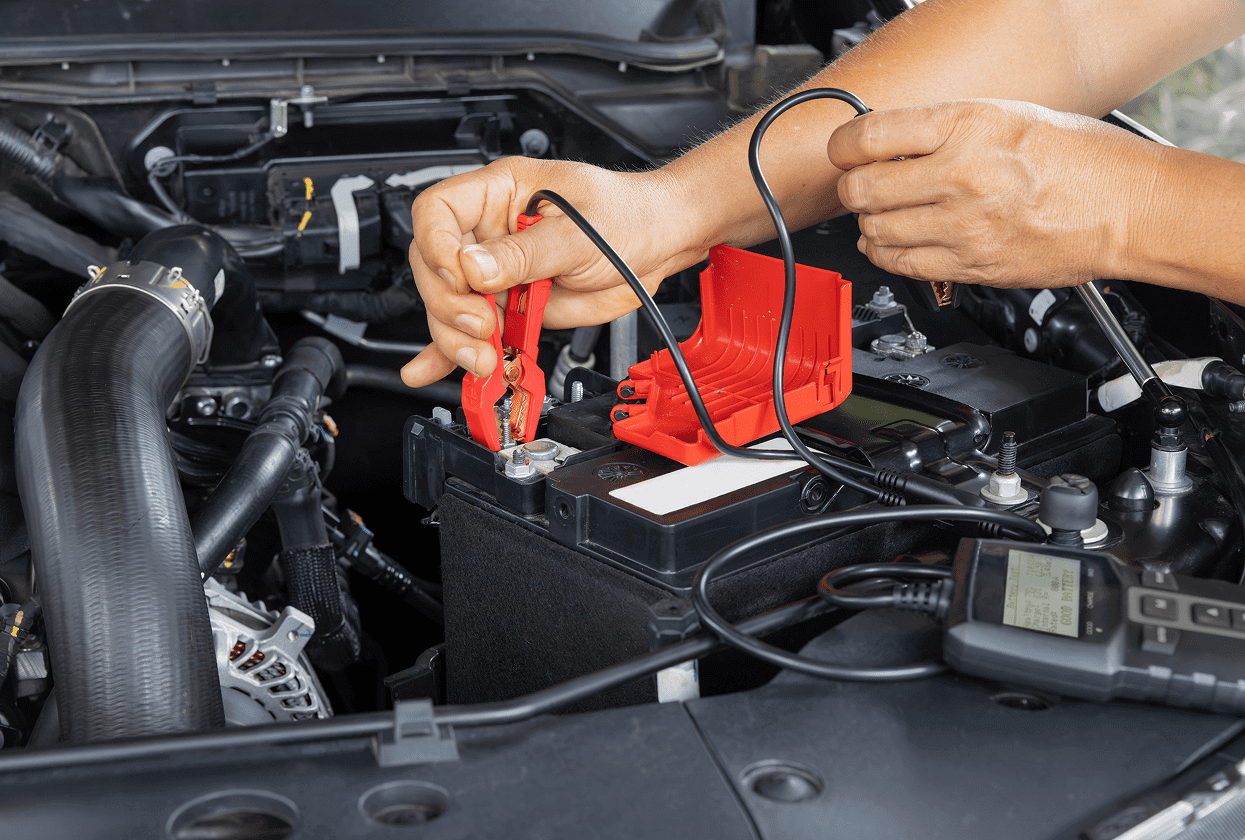 Hands connecting car battery jumper cables.