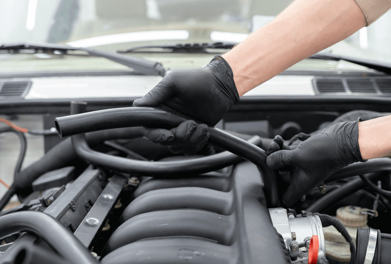 Mechanic working on car engine hoses.
